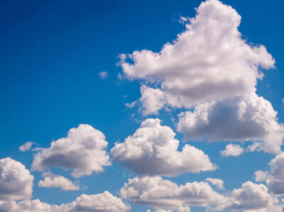 Puffy white cumulus clouds scattered across a bright blue sky.